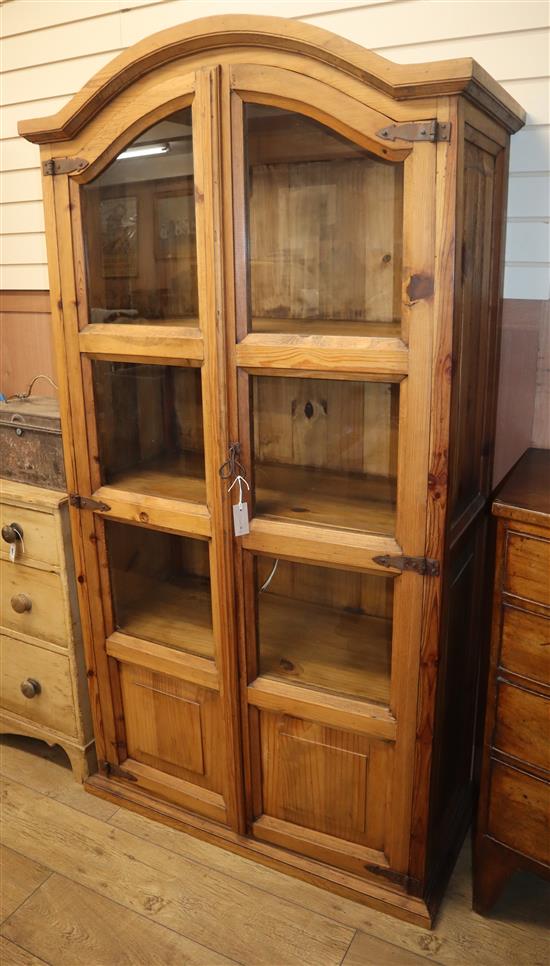 A pine two door glazed cabinet with arched top, H.195cm